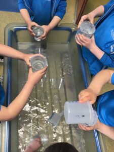 Children exploring water using cups and containers