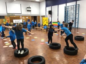 Year 1 children taking part in an indoor team challenge